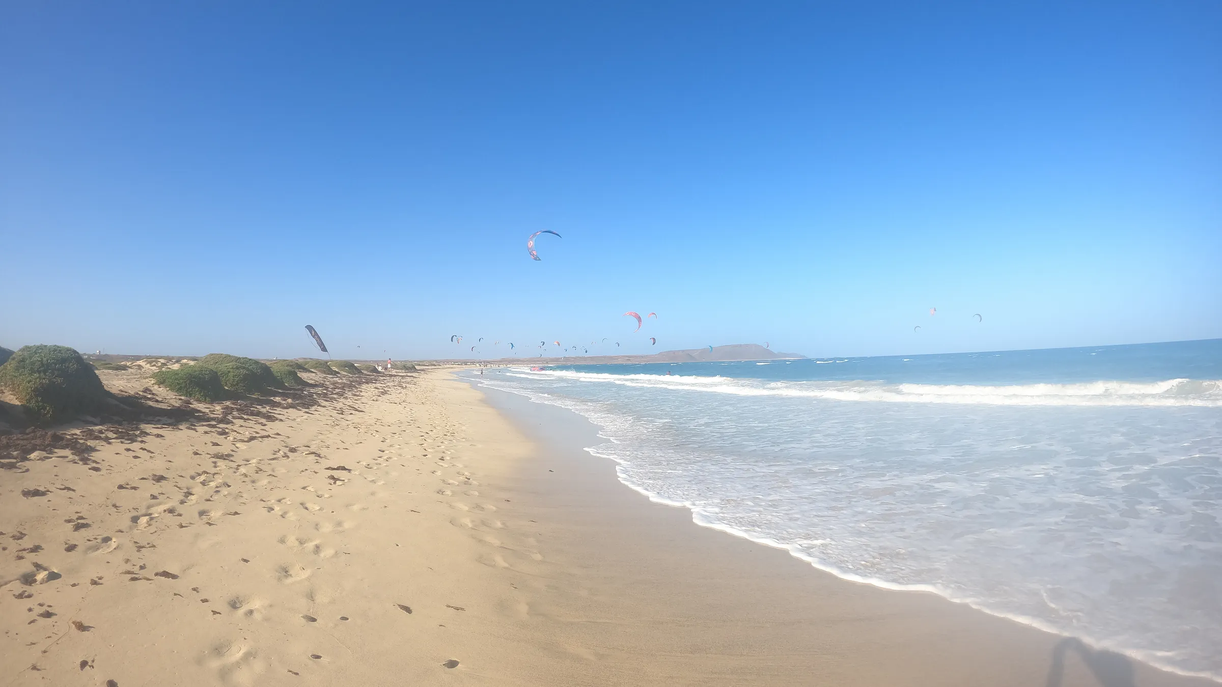Het lange zandstrand van Kite Beach met kites boven zee
