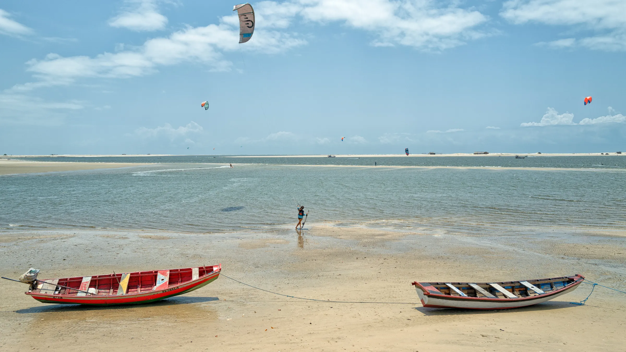 Kites boven het ondiepe water bij Atins, met twee vissersbootjes op het zand