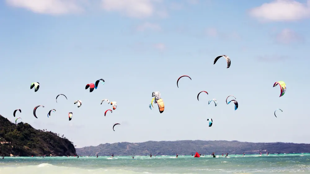 Tientallen kites boven het turquoise water van Bulabog Beach op Boracay