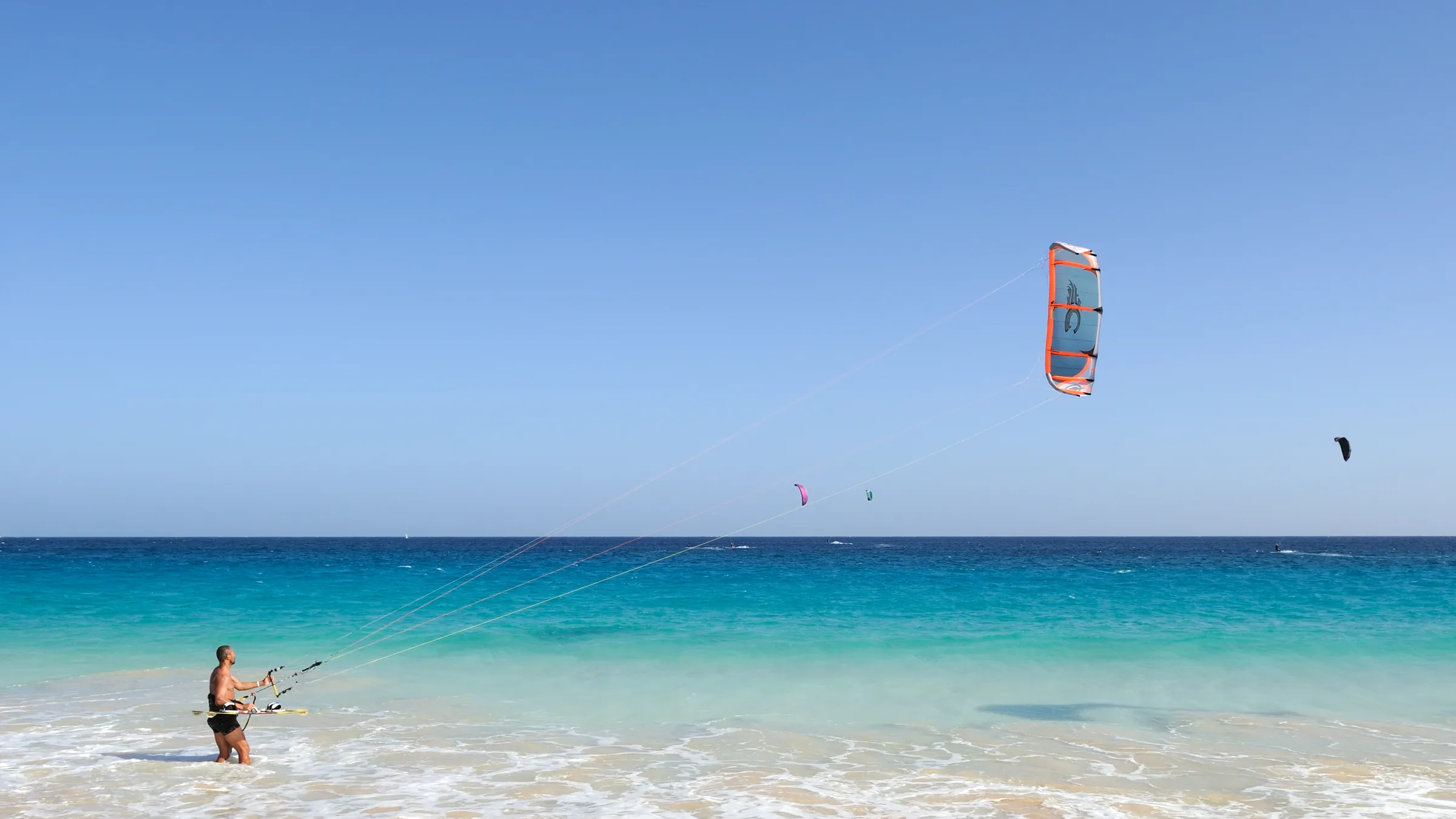 Kiter in turquoise water bij Sal, met zijn kite hoog boven zee