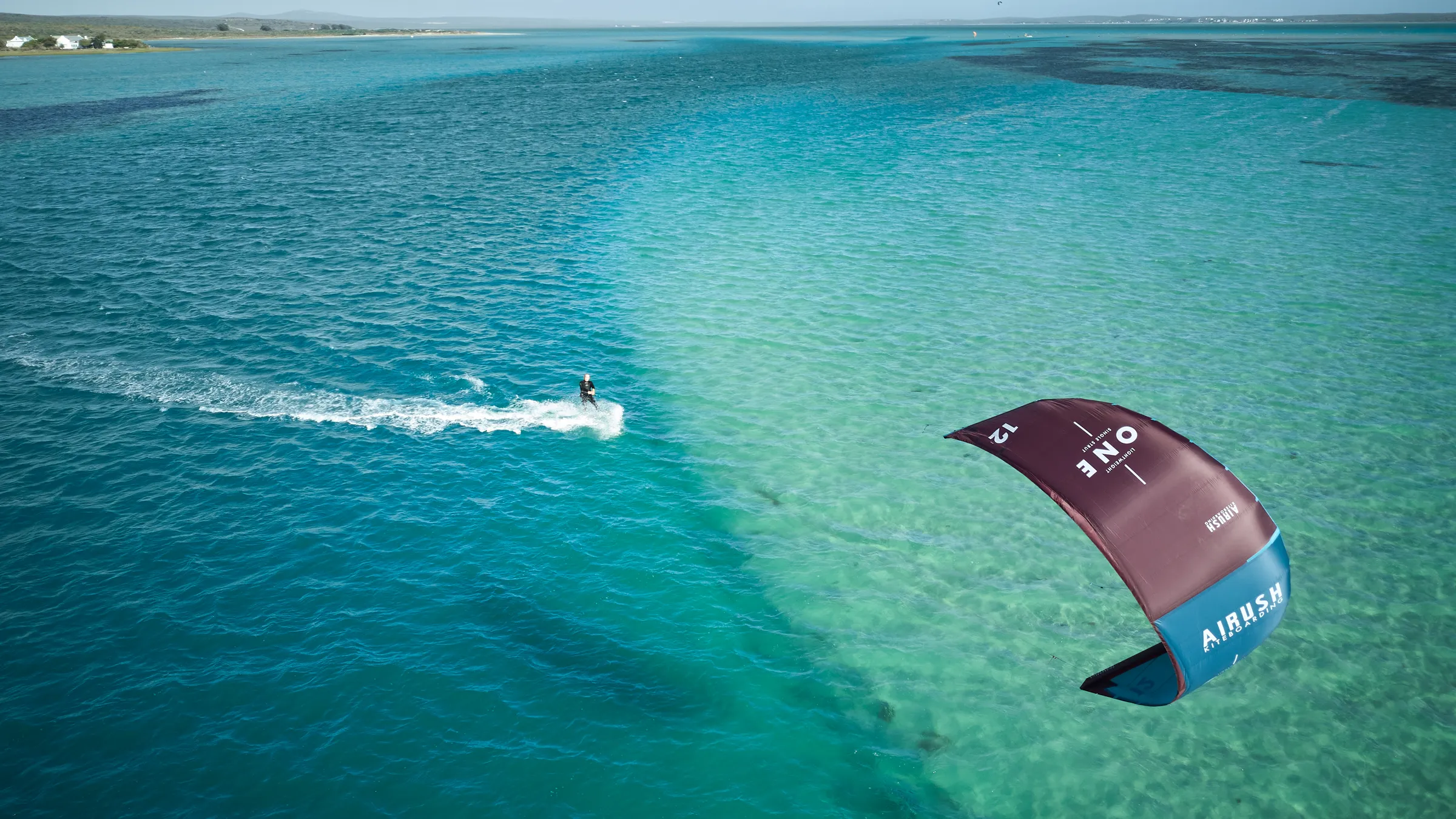 Kitesurfer op het vlakke, turquoise water van de lagune van Langebaan