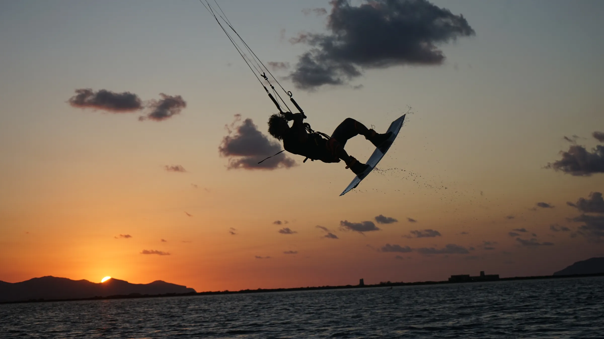 Kitesurfer in een sprong boven de lagune van Lo Stagnone bij zonsondergang