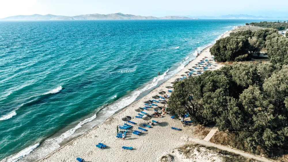 Luchtfoto van het lange zandstrand van Marmari op Kos met golven en parasols