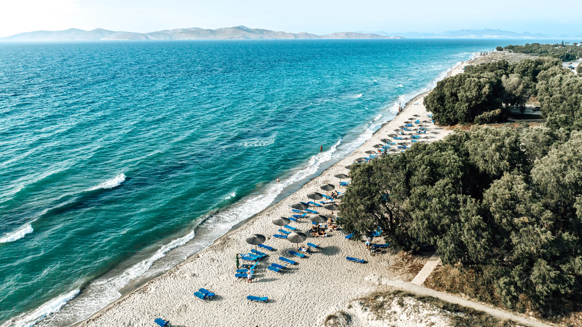 Luchtfoto van het lange zandstrand van Marmari op Kos met golven en parasols