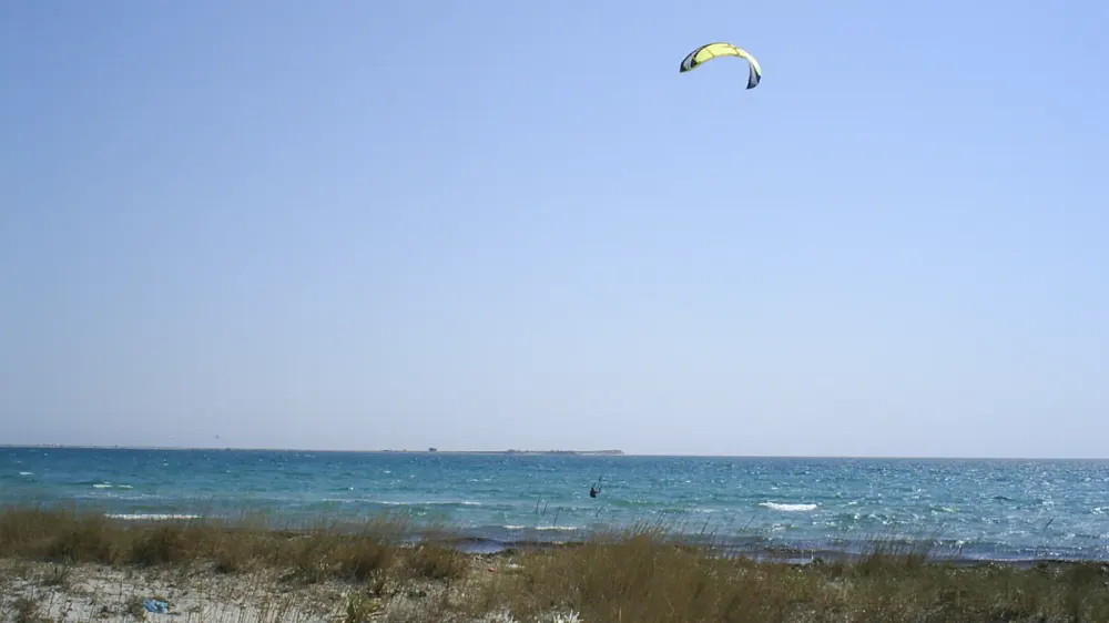 Kitesurfer met een gele kite boven de baai van Keros op Limnos