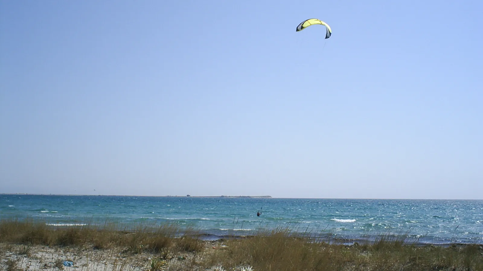 Kitesurfer met een gele kite boven de baai van Keros op Limnos