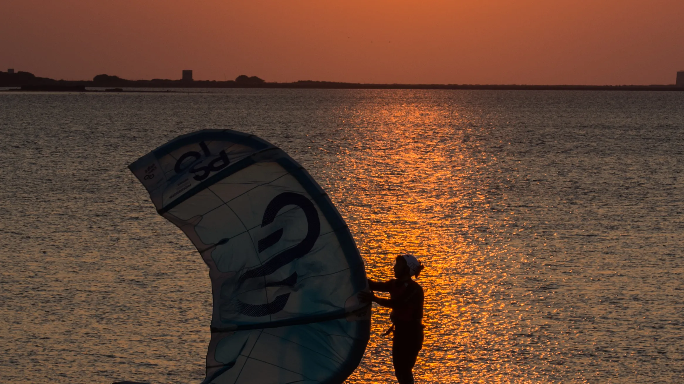 Kiter met zijn kite in het ondiepe water van Lo Stagnone bij zonsondergang