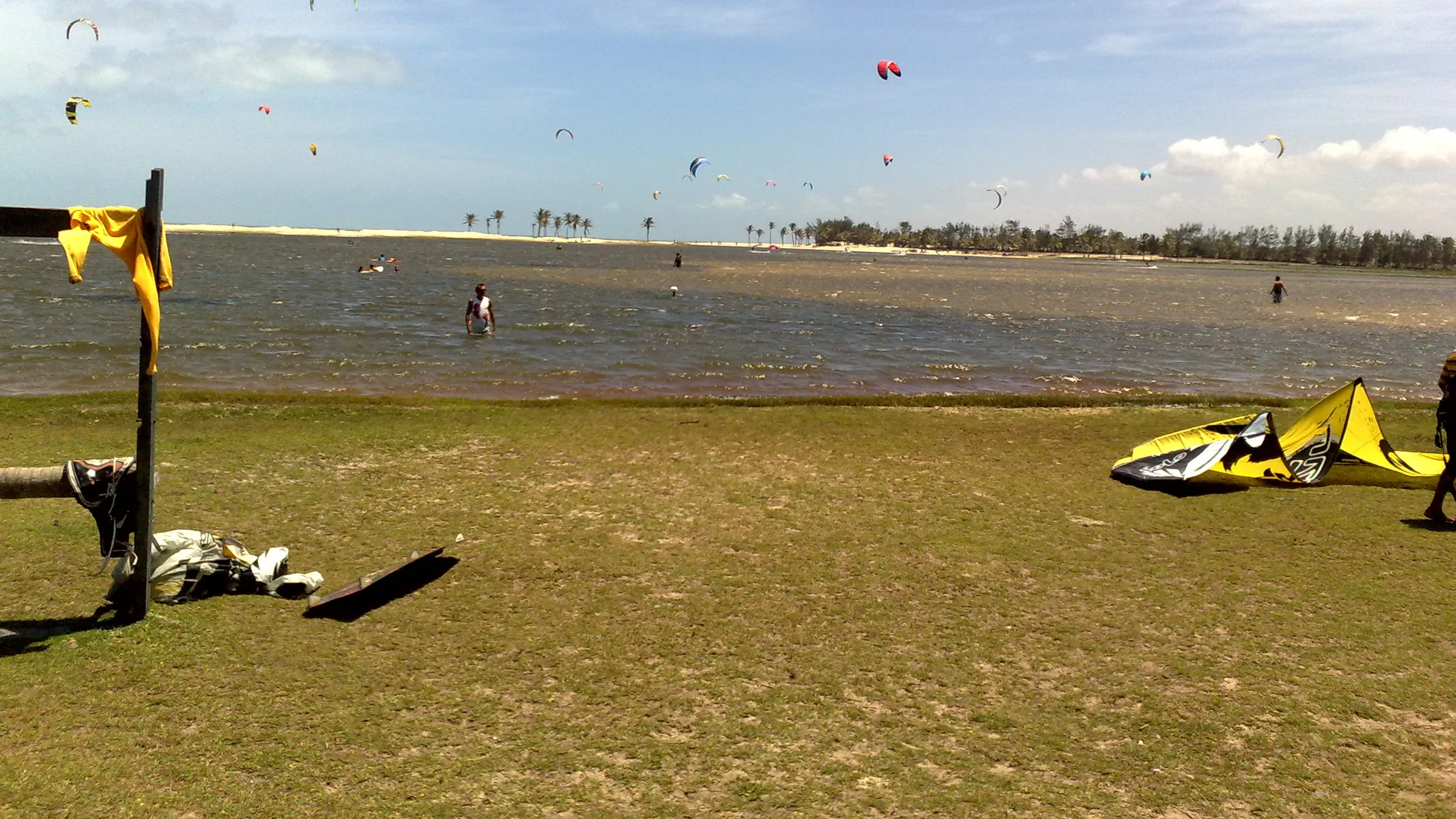 Kites boven de lagune van Cauípe, met kitespullen op het gras aan de oever