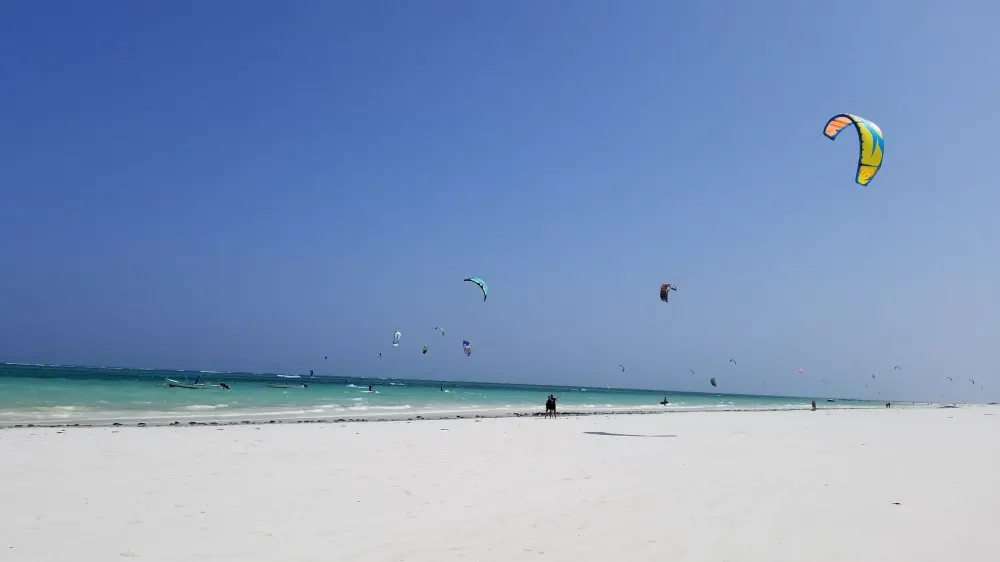 Tientallen kites boven de lagune bij Galu, met het witte strand op de voorgrond