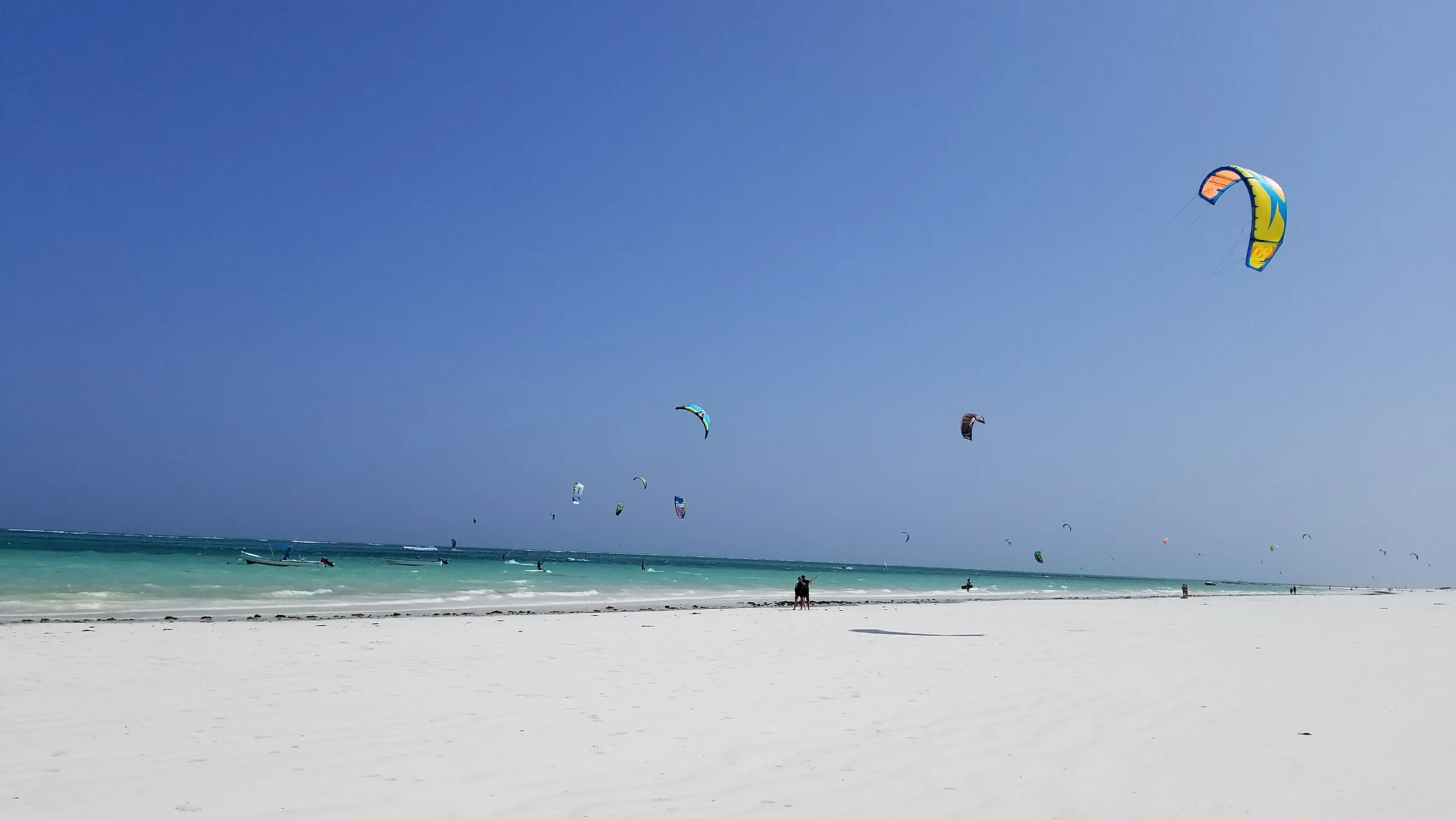 Tientallen kites boven de lagune bij Galu, met het witte strand op de voorgrond