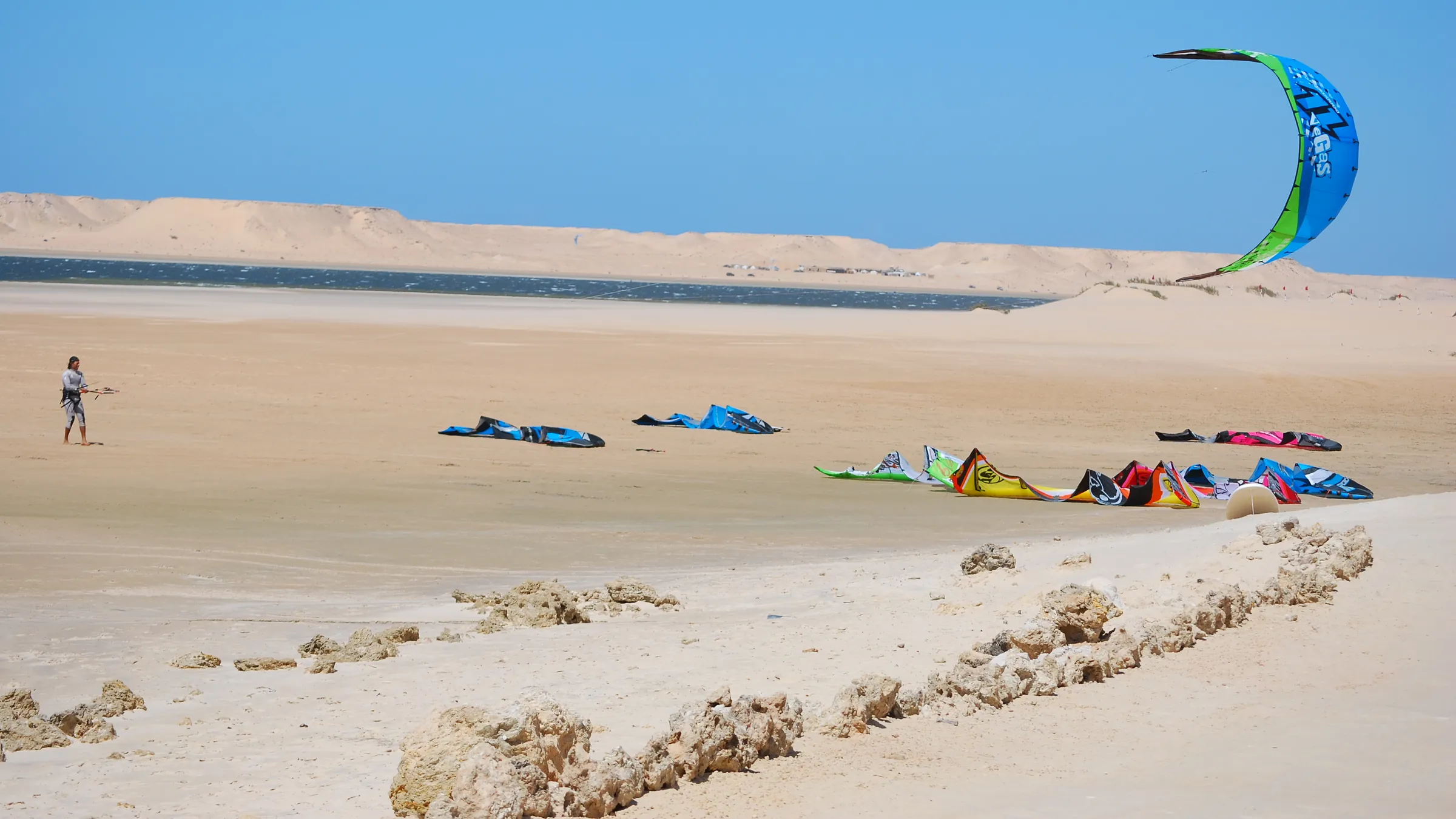 Kites op het zandstrand aan de lagune van Dakhla, met woestijnheuvels erachter