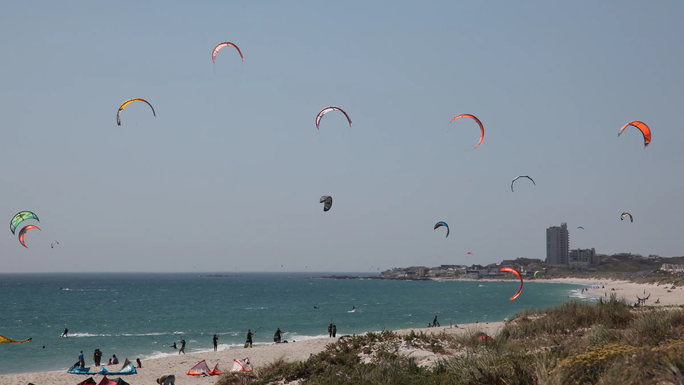 Tientallen kites boven het strand bij Bloubergstrand