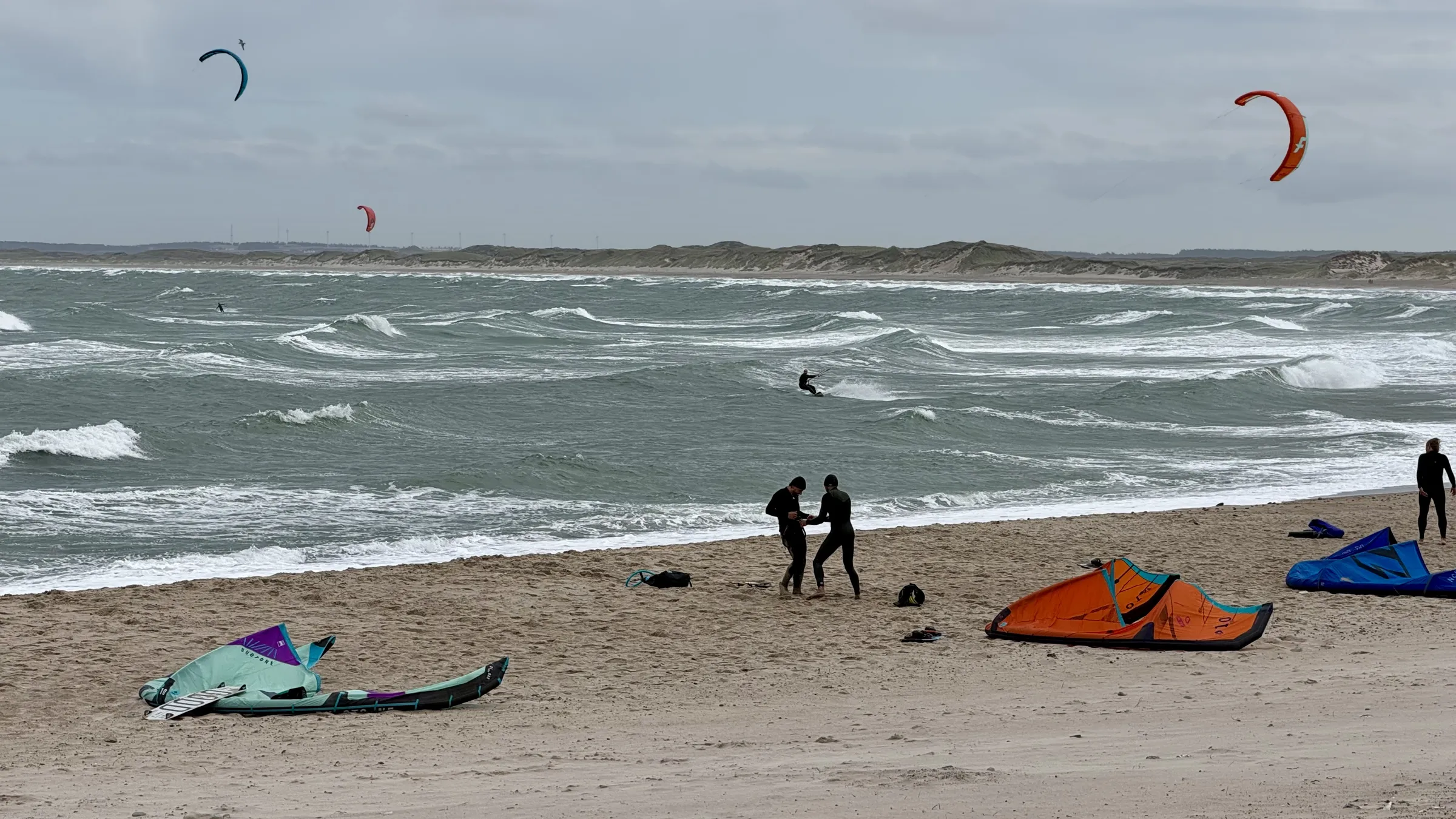 Kites op het strand van Klitmøller terwijl kiters de branding in gaan