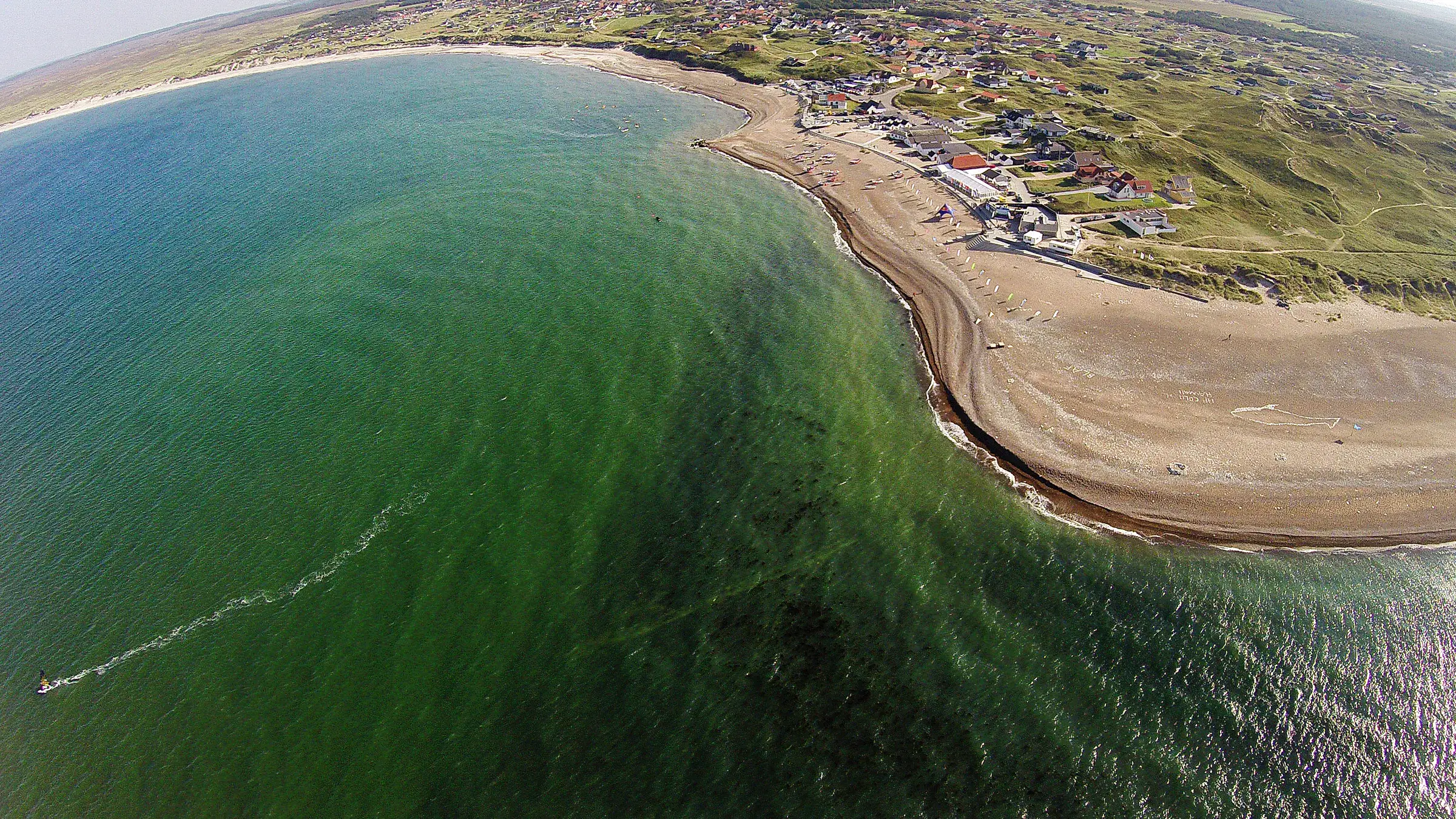 Luchtfoto van de baai van Klitmøller met het dorp, het strand en het rif