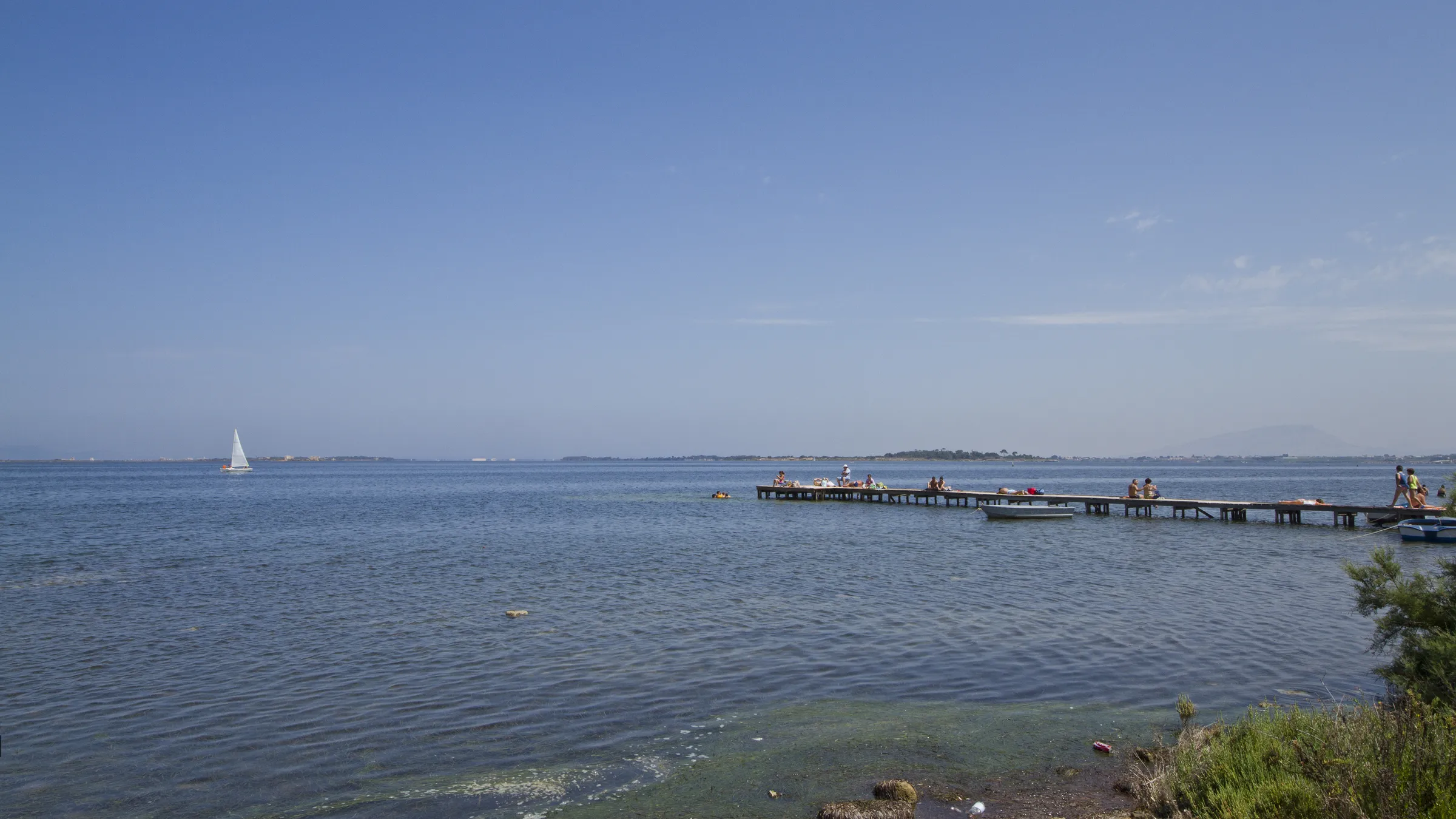Het vlakke, ondiepe water van de lagune Lo Stagnone met een houten steiger
