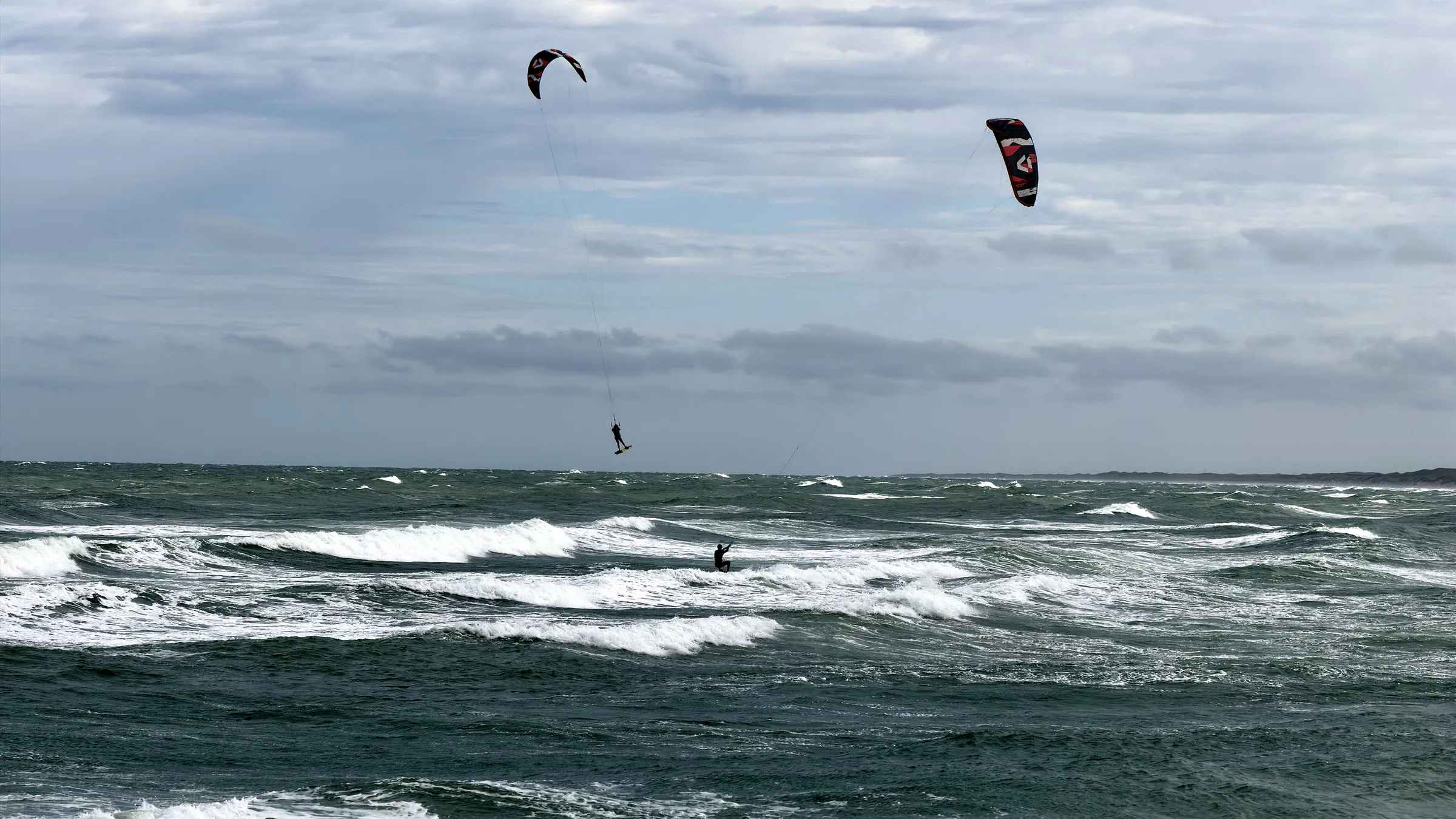 Kitesurfer in een sprong boven de woeste Noordzee bij Nørre Vorupør