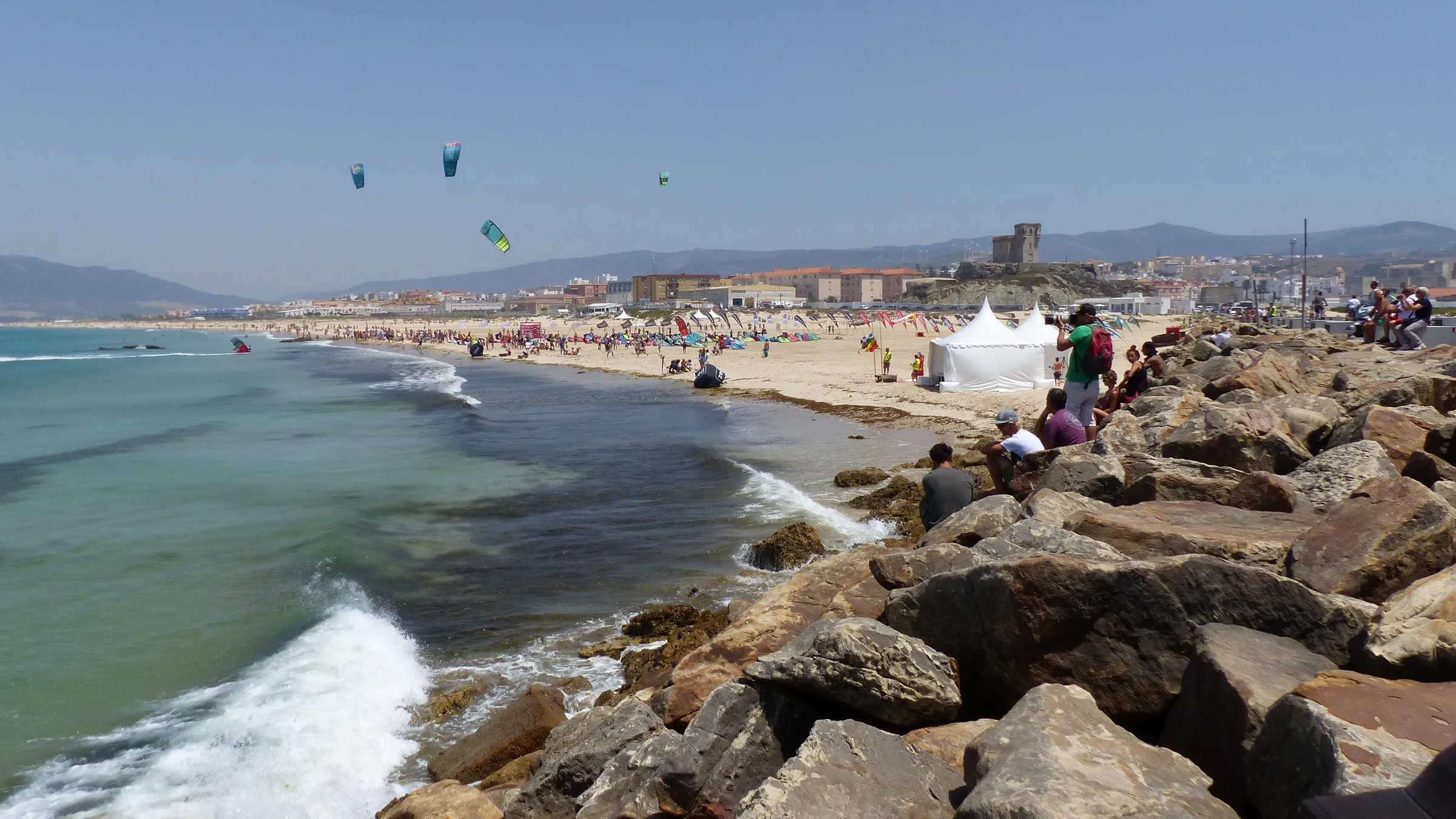 Playa de Los Lances gezien vanaf de dam naar het eiland, met kites boven het strand