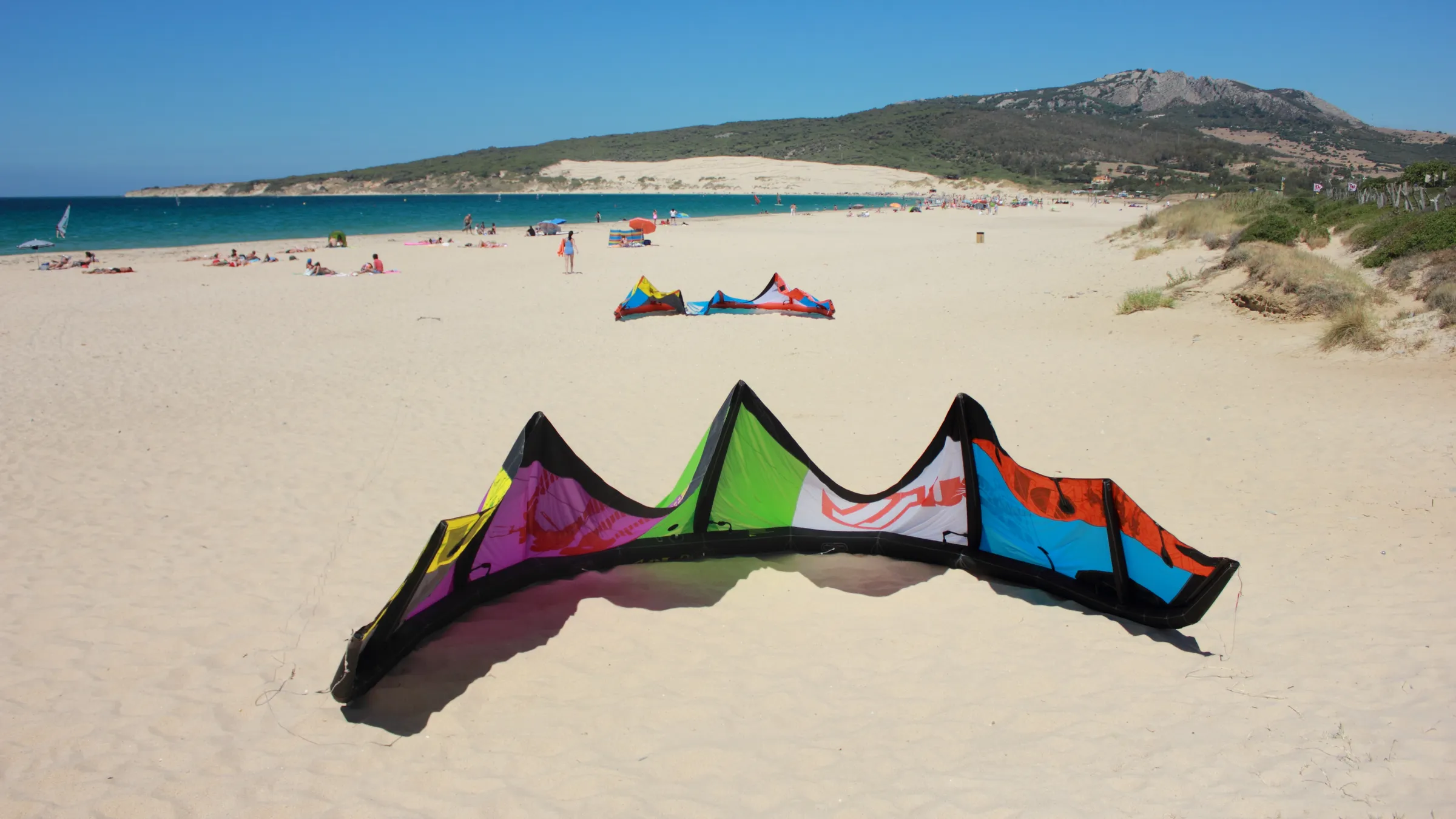 Kite op het witte zand van Valdevaqueros, met het grote duin op de achtergrond