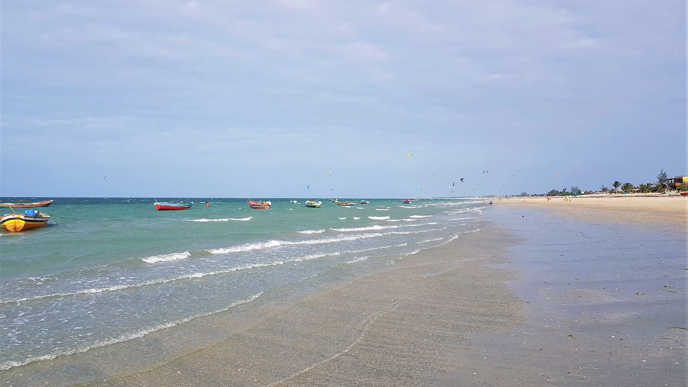 Het brede strand van Preá met vissersbootjes en kites in de verte