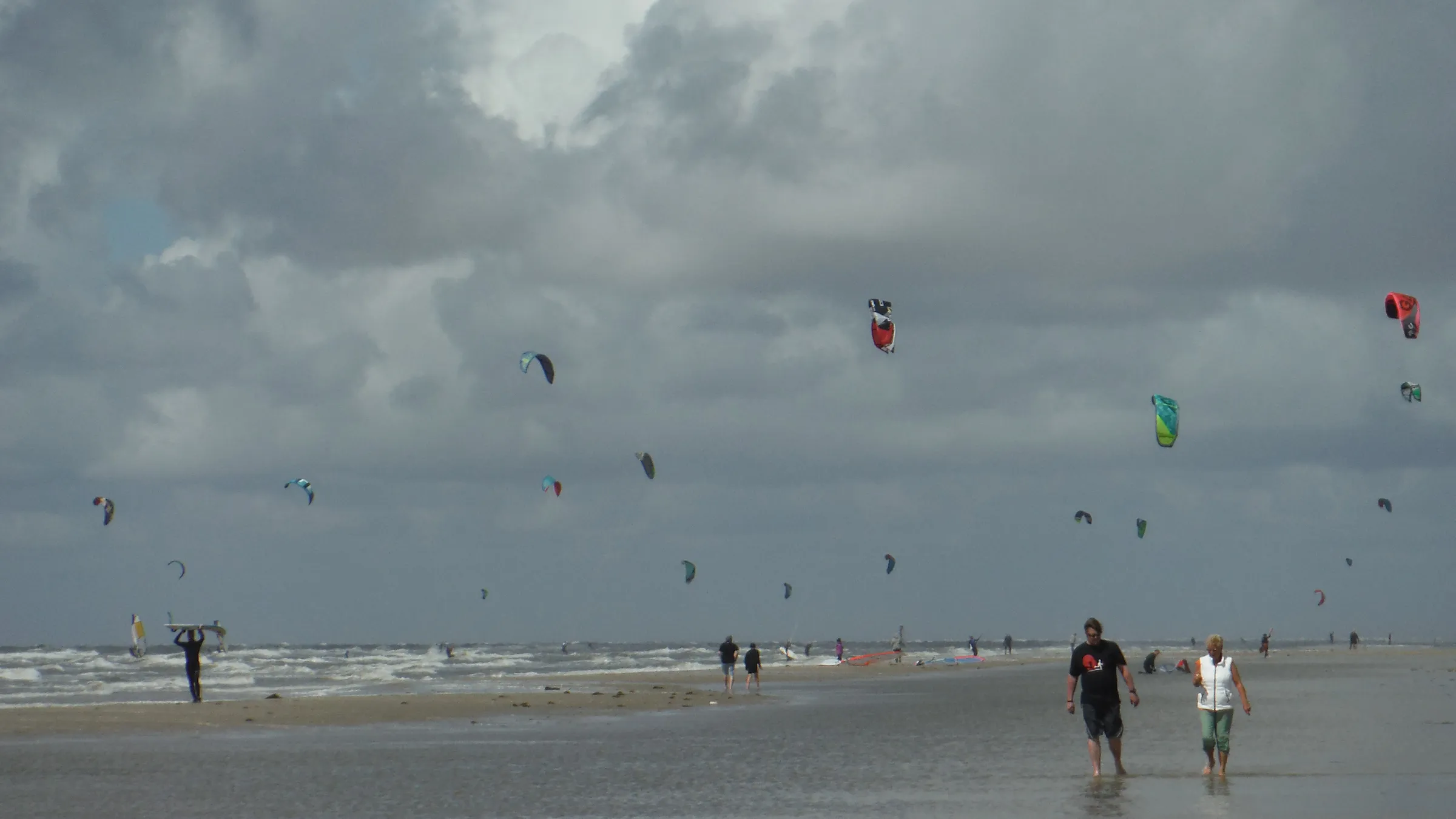 Tientallen kites boven het brede strand van Rømø onder een wolkenlucht