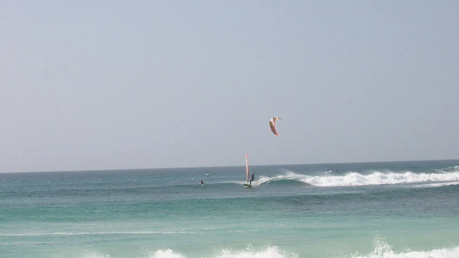 Kiter en windsurfer tussen de golven aan de zuidwestkust van Sal