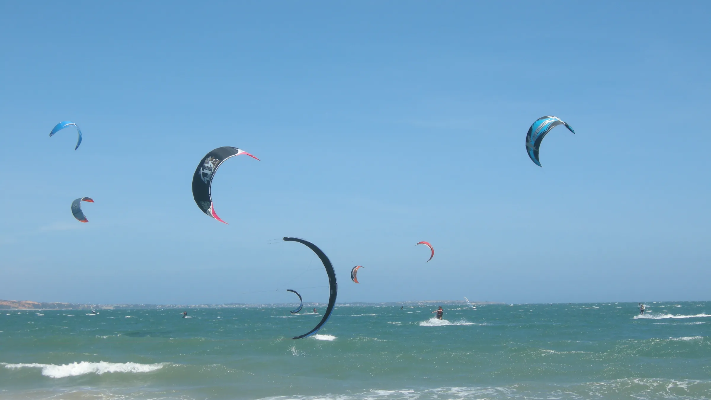 Tientallen kites boven de zee bij Mui Ne onder een blauwe lucht