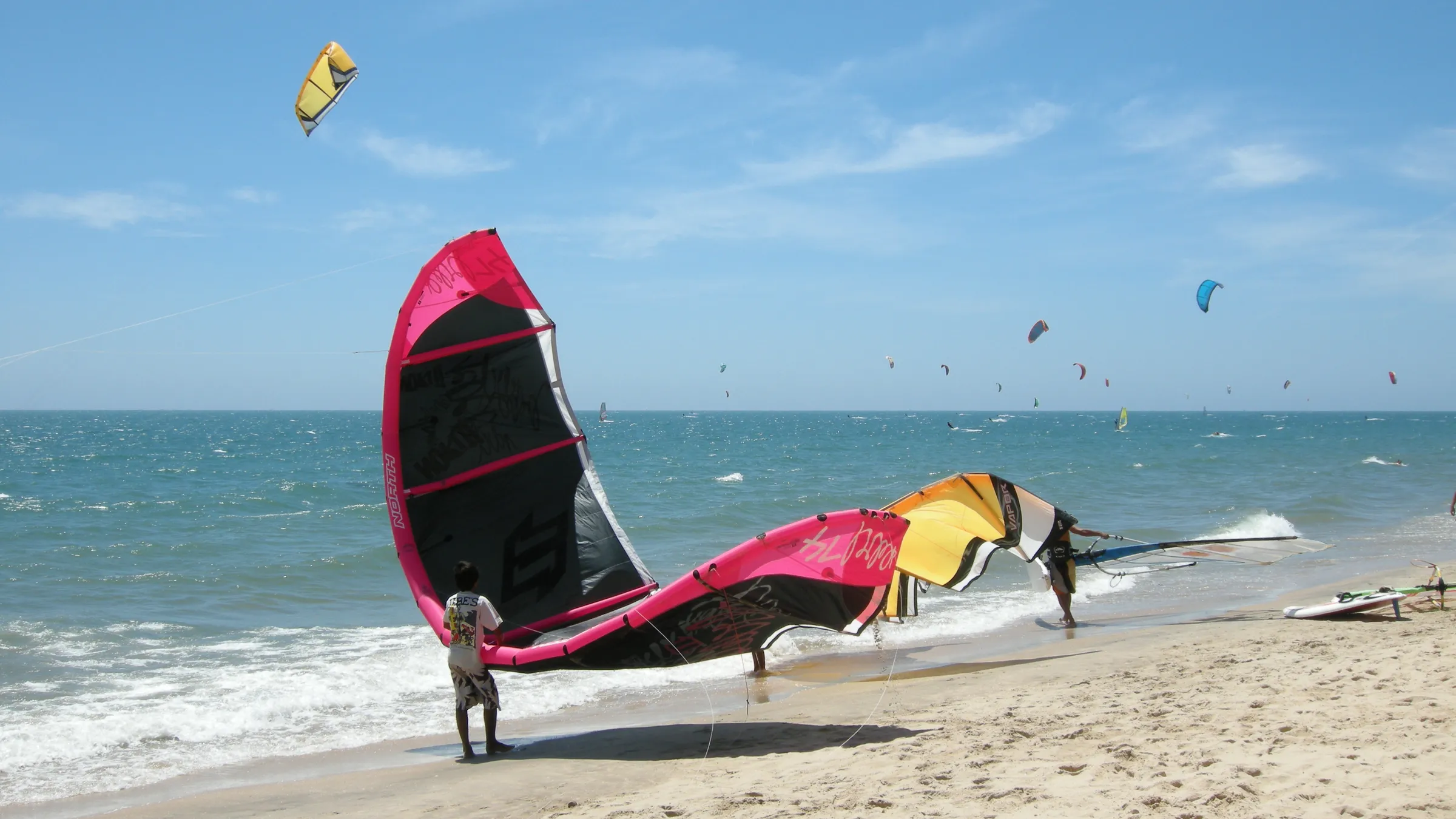 Kites op het strand van Mui Ne, met veel kites boven zee op de achtergrond