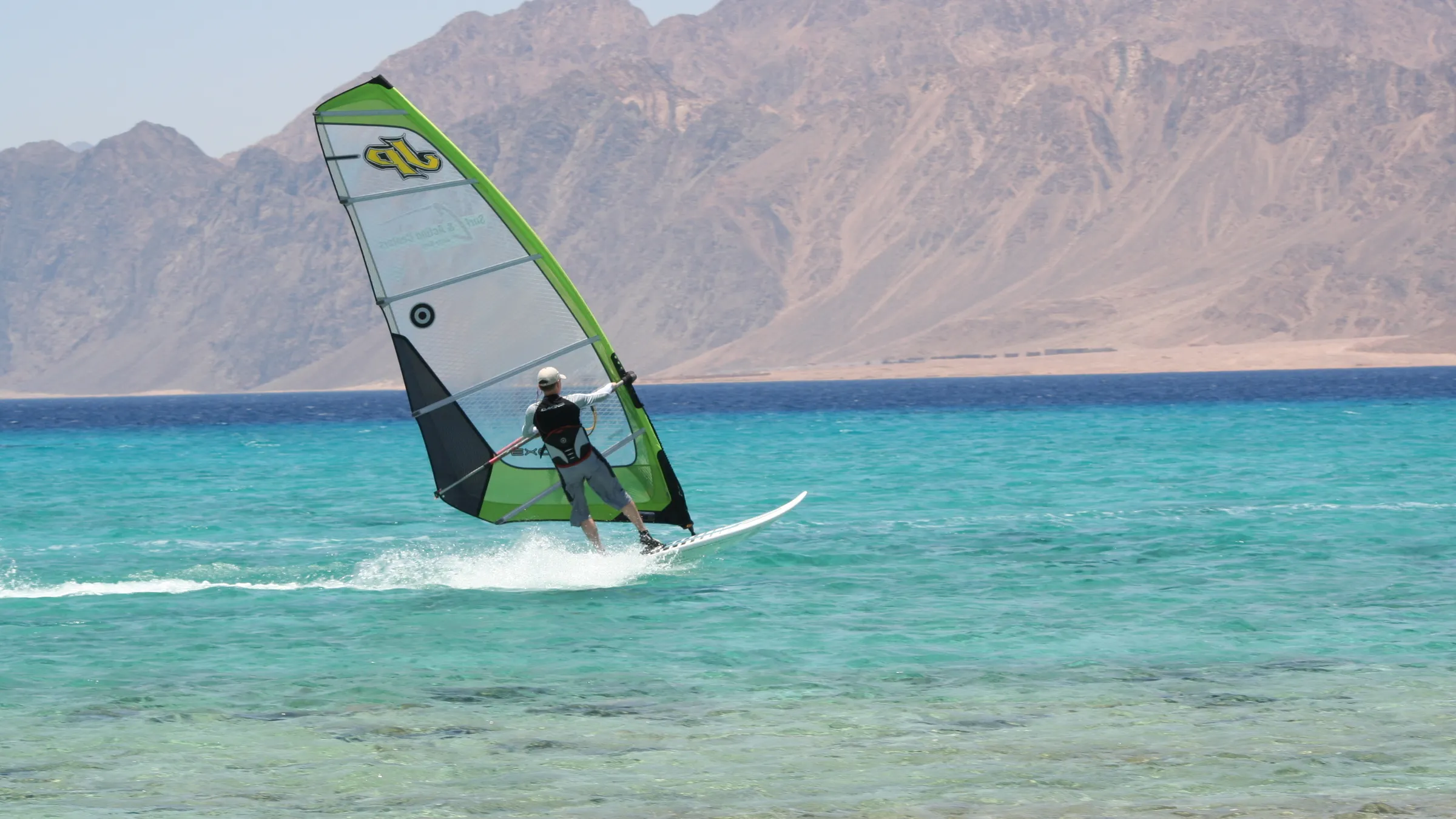 Windsurfer op het heldere water van de lagune van Dahab, met de Sinaïbergen op de achtergrond