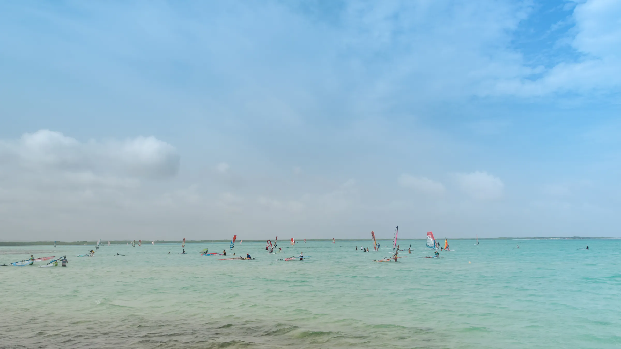 Veel windsurfers op Lac Bay onder een lichte bewolking